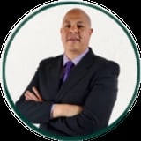 Professional headshot of a man in a dark blazer and purple tie with arms crossed