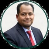 Professional headshot of a man in a dark blazer and red tie against a white background