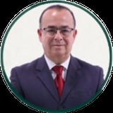 Professional headshot of a man in a dark blue suit and red tie wearing glasses, against a light background in a circular frame